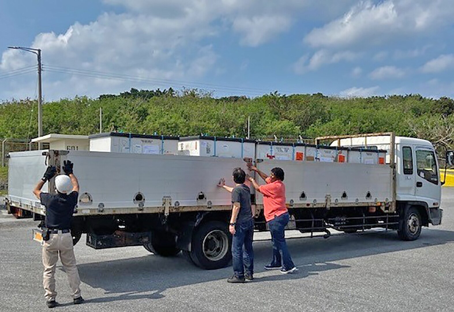 Three associates secure pallets on truck.