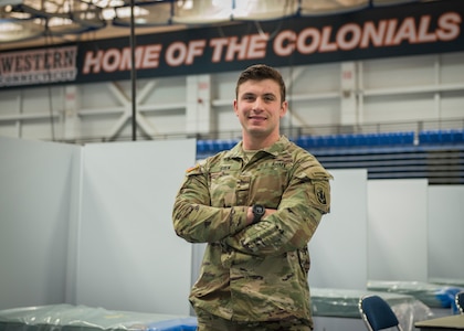 U.S. Army Sgt. Luk Silk, 1-102nd Infantry Regiment, in front of field hospital beds at the O’Neill Center at Western Connecticut State University in Danbury, Connecticut, April 2, 2020. Silk, 23, from Glastonbury, is one of many Connecticut Army and Air National Guard members who set up field hospital equipment at the gymnasium for potential patient use in response to the COVID-19 pandemic.