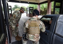 Chief Master Sgt. Michael Cole, left, 628th Air Base Wing command chief master sergeant, and Senior Airman Khristian Breaux, 628th Security Forces Squadron entry controller, direct and inform visitors about installation changes at Joint Base Charleston, S.C., March 31, 2020.
