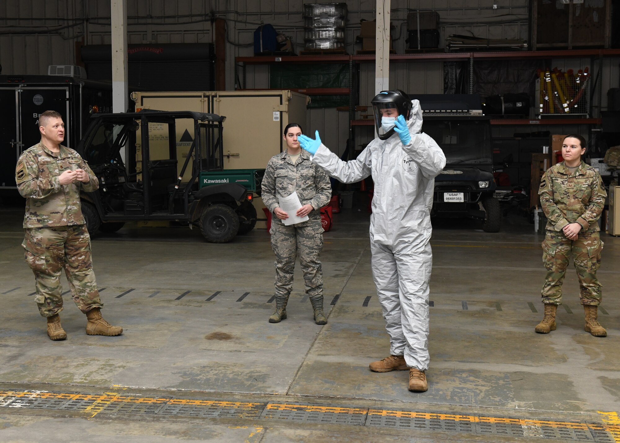 Senior Airman Dennis McAnnally, 9th Operational Medical Readiness Squadron Bioenviromental Engineering technician, center right, demonstrates how to properly don personal protective equipment, Mar. 28, 2020 at Beale Air Force Base, California. The training was provided to prepare Airmen for COVID-19 response efforts. (U.S. Air Force photo by Airman 1st Class Luis A. Ruiz-Vazquez)