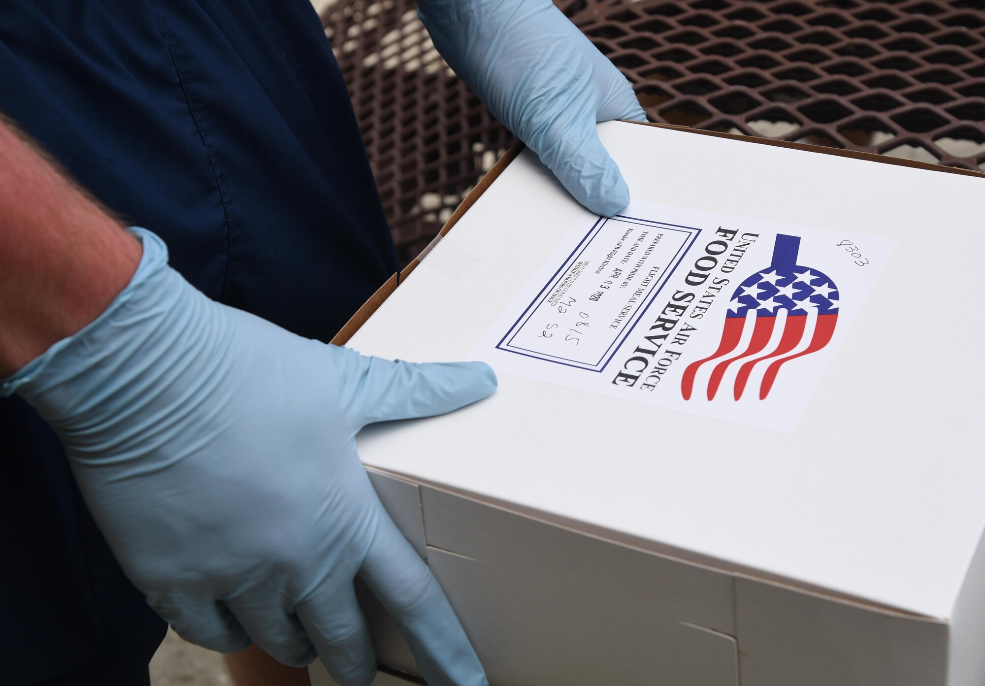 U.S. Air Force Airman 1st Class Seth Haddix, 81st Training Wing public affairs photojournalist, sorts box lunches outside of a lodging building at Keesler Air Force Base, Mississippi, April 3, 2020. Three meals are delivered daily to Keesler personnel that are in 14-day quarantine/isolation, which are being housed inside a select number of lodging buildings in the same area called Comfort Cove. Keesler is taking precautionary measures across the base to reduce the chances our personnel contract or spread the disease. (U.S. Air Force photo by Kemberly Groue)