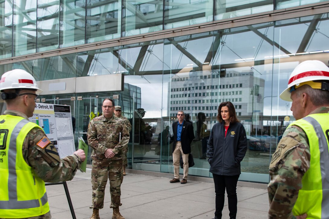 People in front of a building receive a briefing.