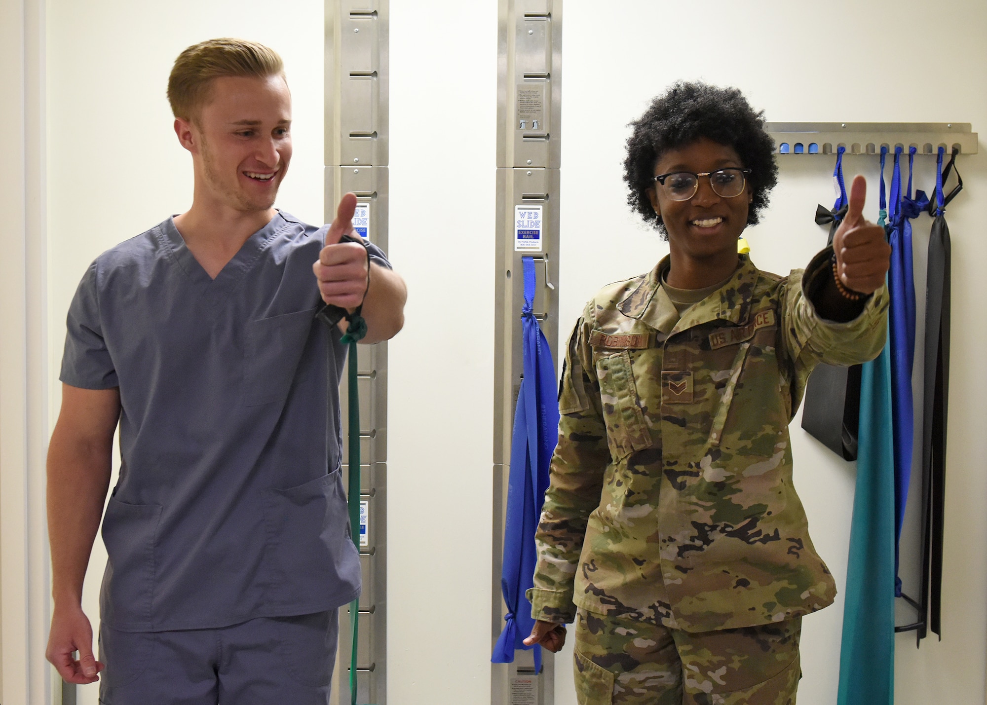 A photo of a U. S. Air Force Airman demonstrating how to perform a physical therapy arm stretch with a band