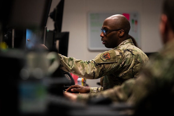 A U.S. Air Force Staff Sergeant is pointing at a computer screen.