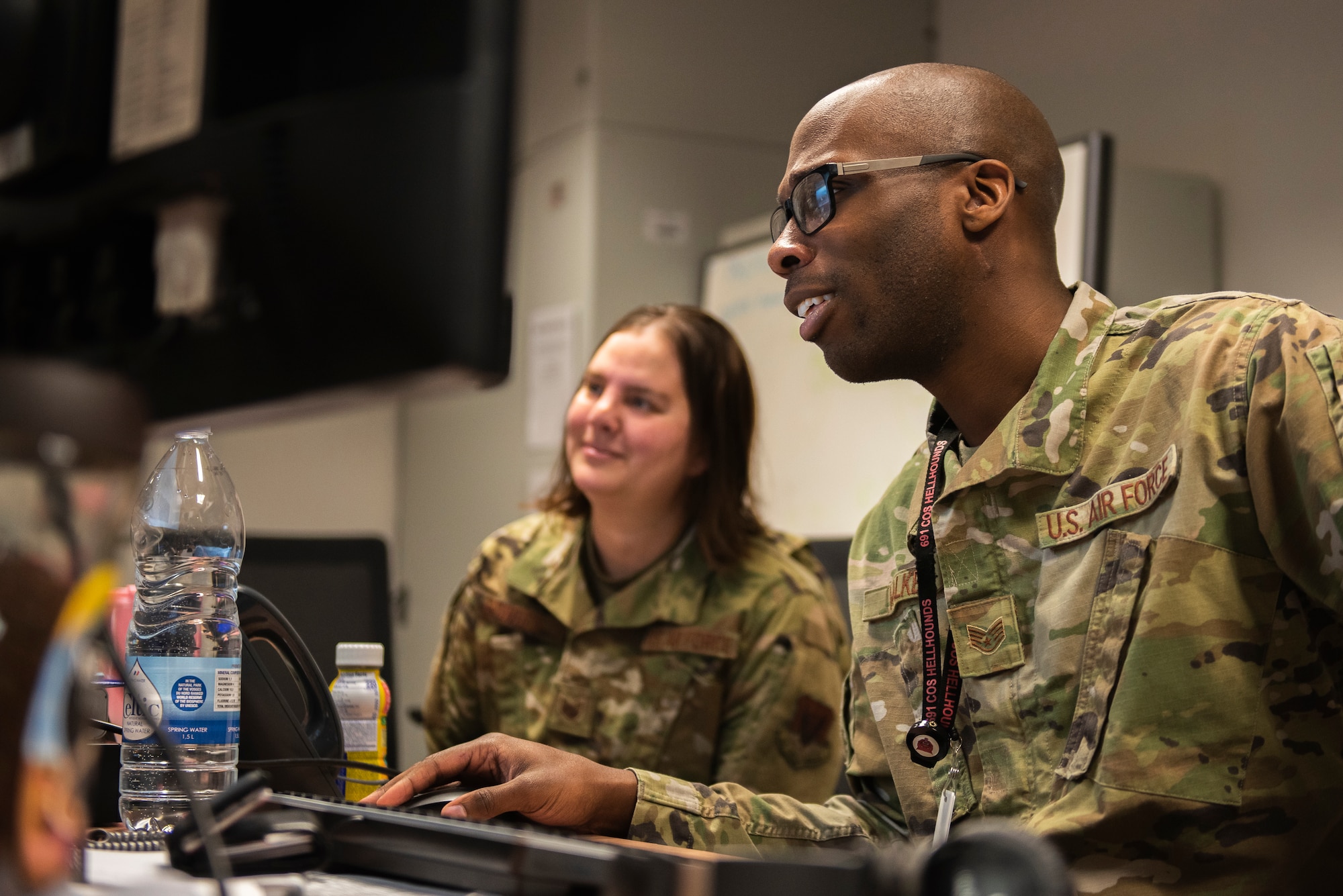 U.S. Airmen look at a computer and discuss data.