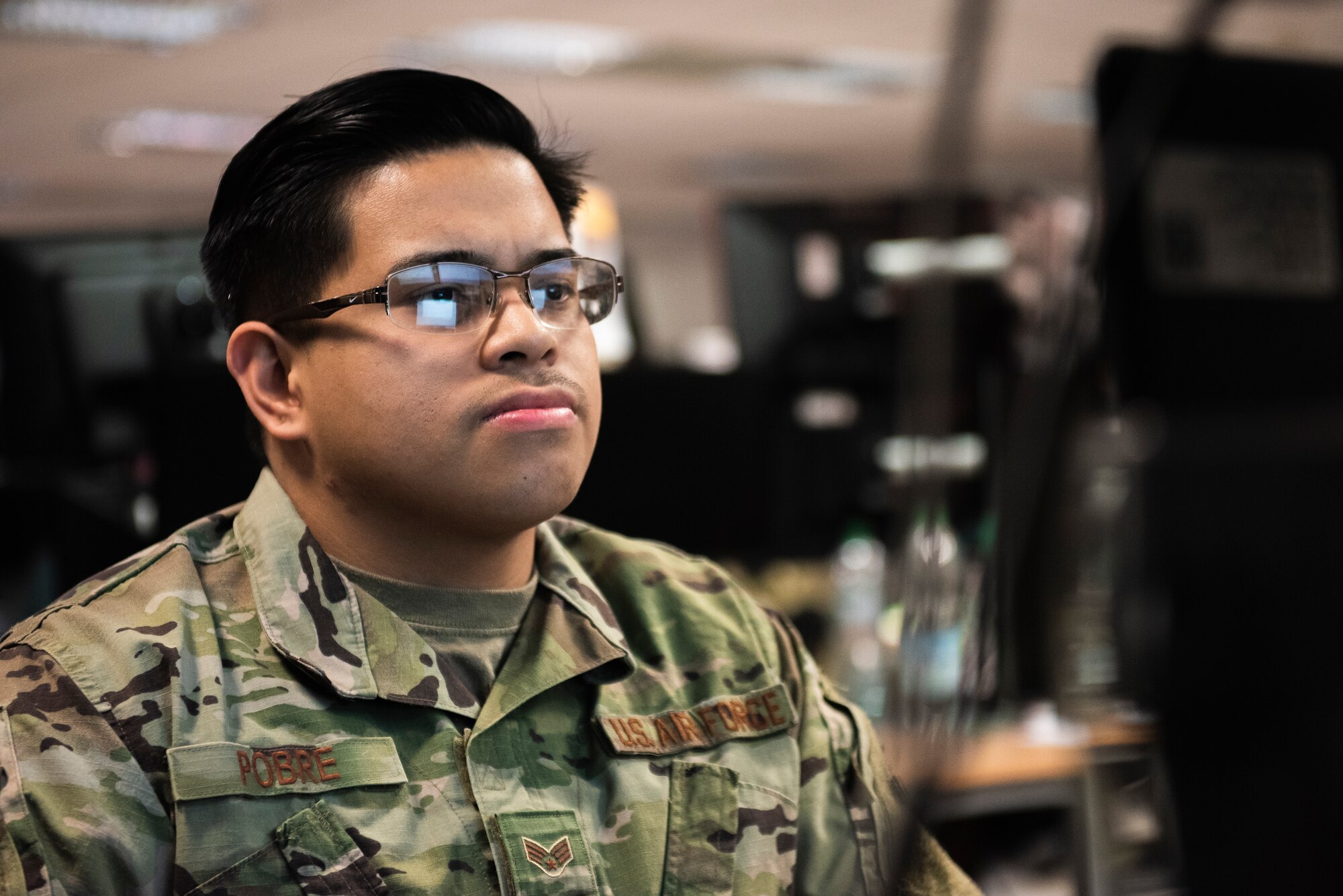A U.S. Airman looks at his computer screen and is reflected off of his eye-glasses.