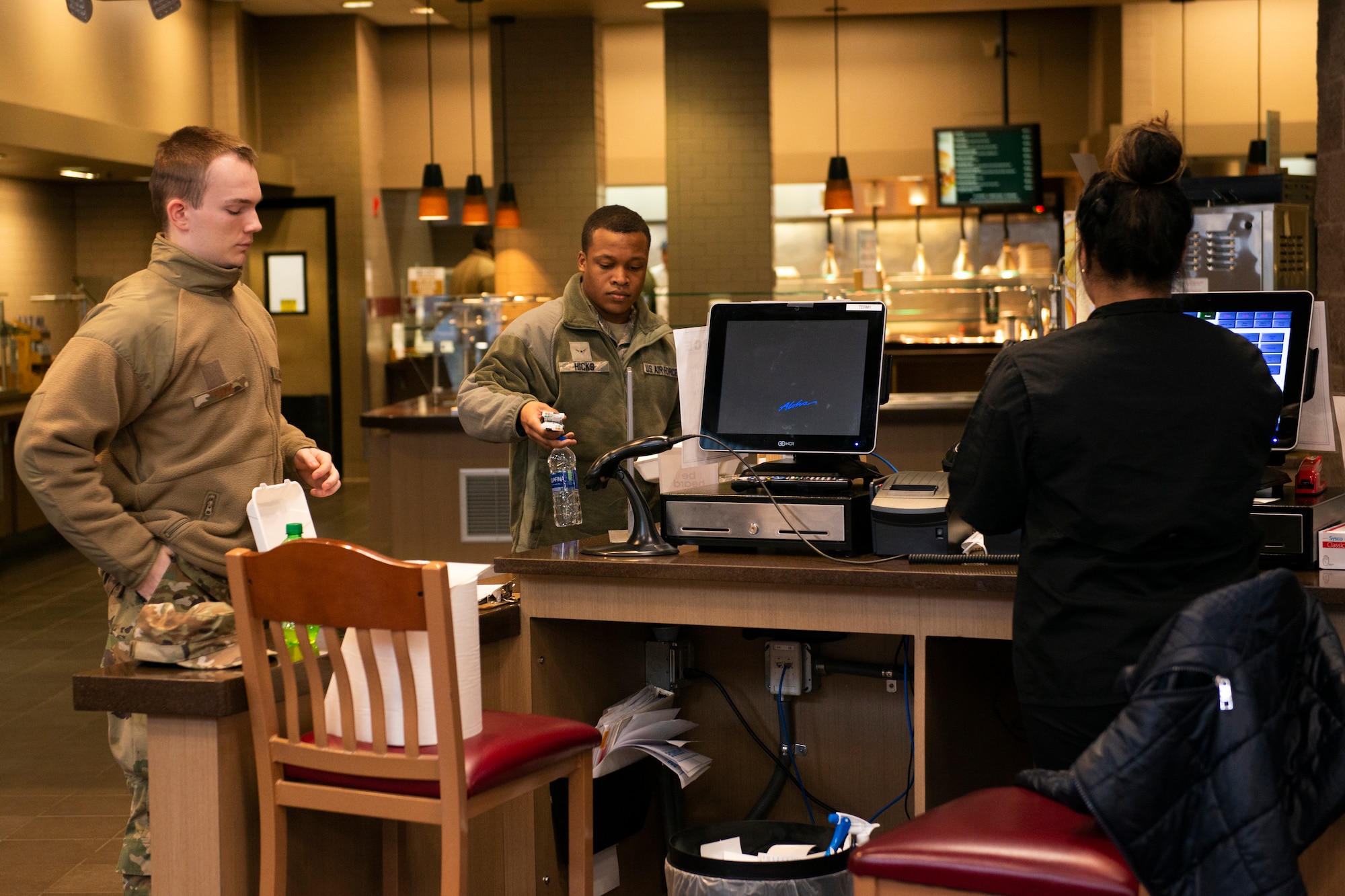 U.S. Airmen demonstrate social distancing while purchasing their food in the Iditarod Dining Facility on Joint Base Elmendorf-Richardson, Alaska, April 2, 2020. The dining facility used signs to remind people to maintain distance as a measure against COVID-19.