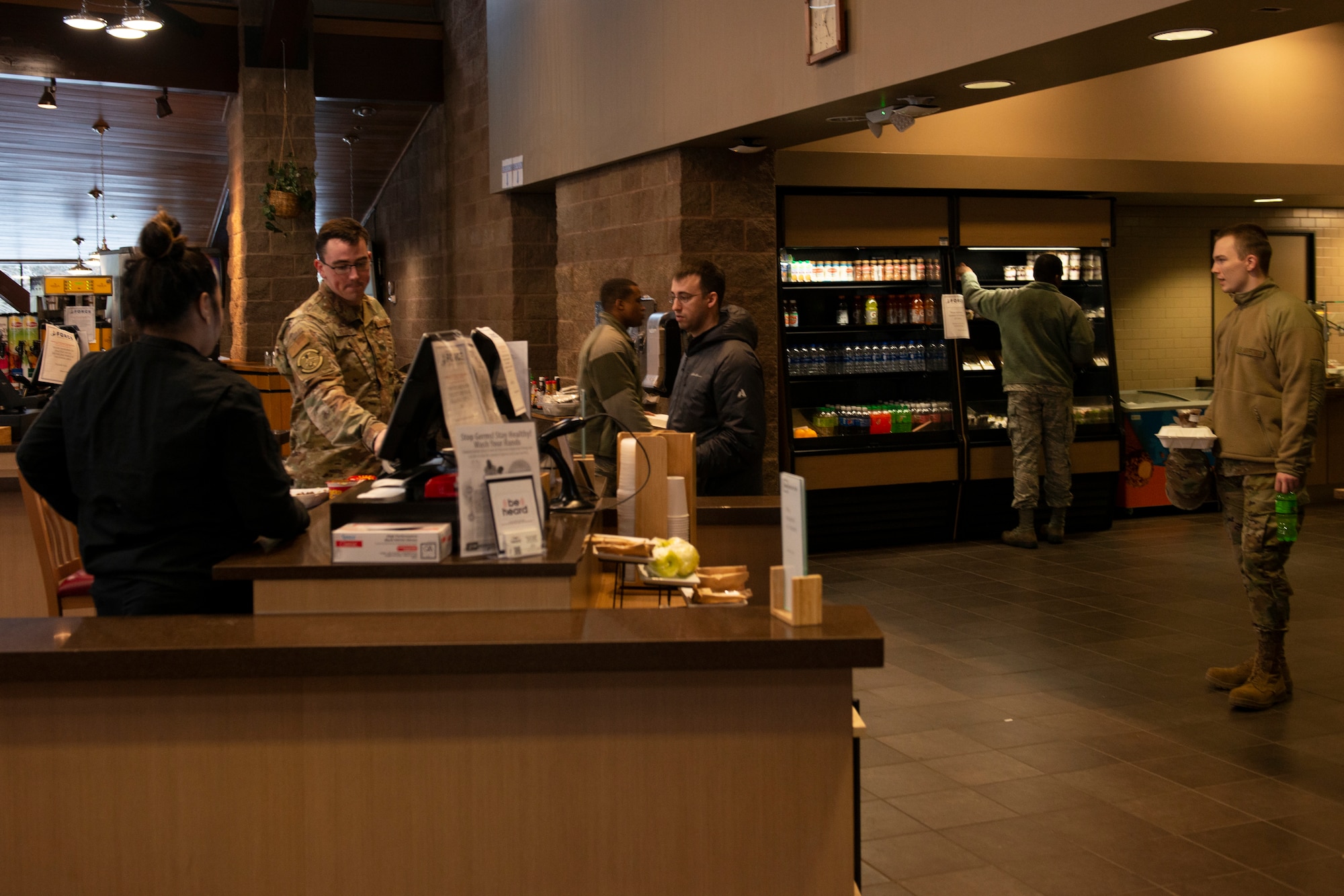 U.S. Airmen demonstrate social distancing while purchasing their food in the Iditarod Dining Facility on Joint Base Elmendorf-Richardson, Alaska, April 2, 2020. The dining facility used signs to remind people to maintain distance as a measure against COVID-19.