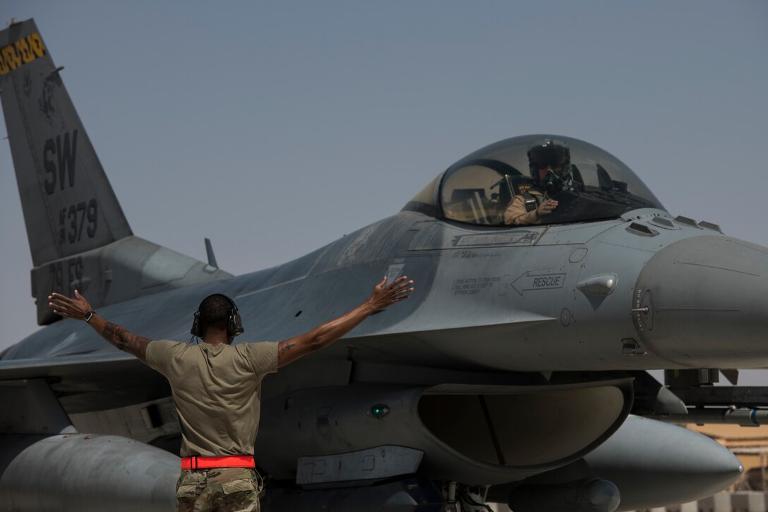 U.S Air Force Staff Sgt. Nathan Stokes, a crew chief with the 380th Expeditionary Aircraft Maintenance Squadron guides a U.S. Air Force F-16 “Viper” Fighting Falcon assigned to the 79th Expeditionary Fighter Squadron at an undisclosed location in the U.S. Central Command area of responsibility, Feb. 14, 2020.