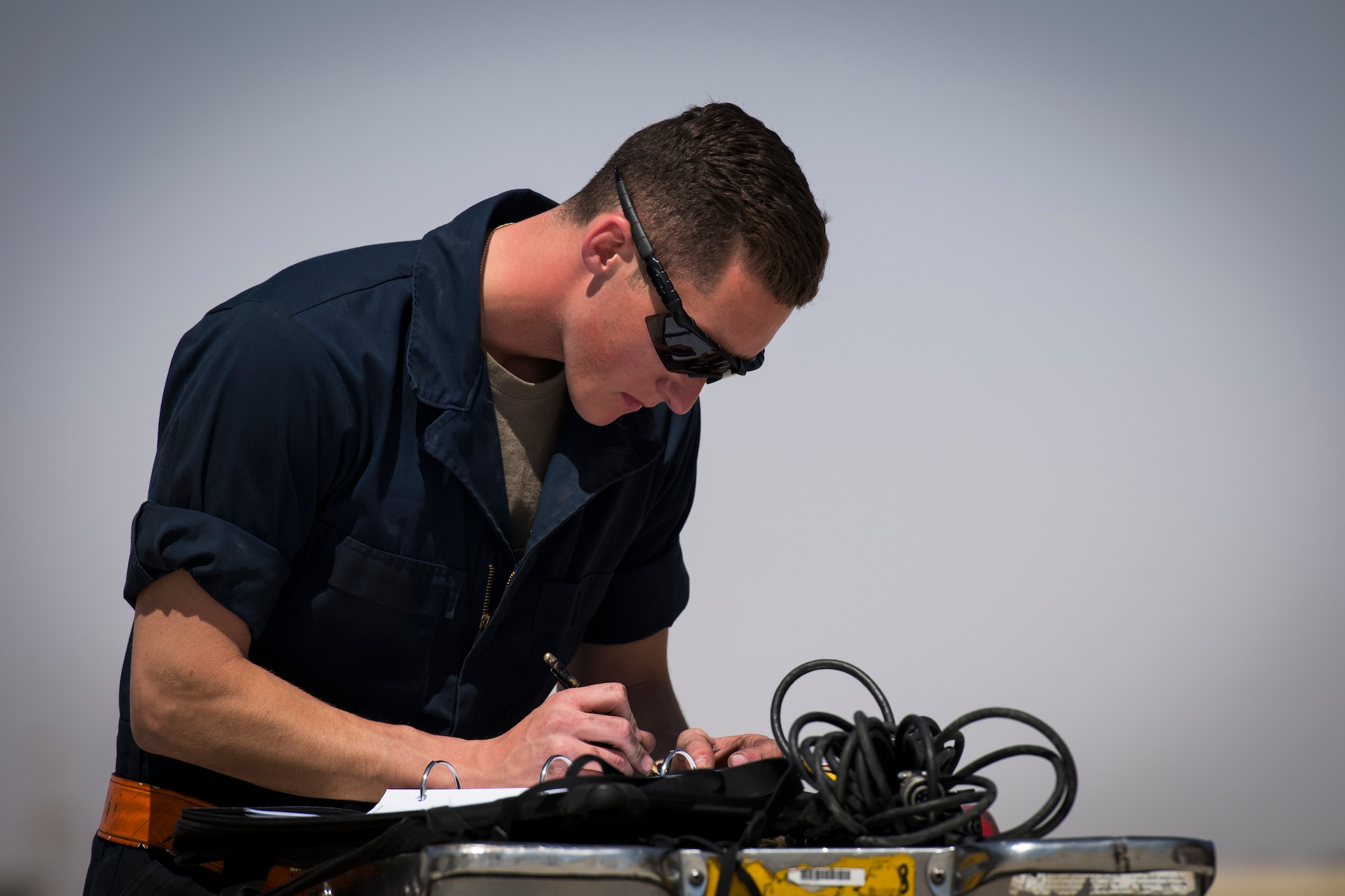 U.S Air Force Airman 1st Class Lucas Haas, a crew chief with the 380th Expeditionary Aircraft Maintenance Squadron fills out maintenance logs at an undisclosed location in the U.S. Central Command area of responsibility, Feb. 14, 2020.
