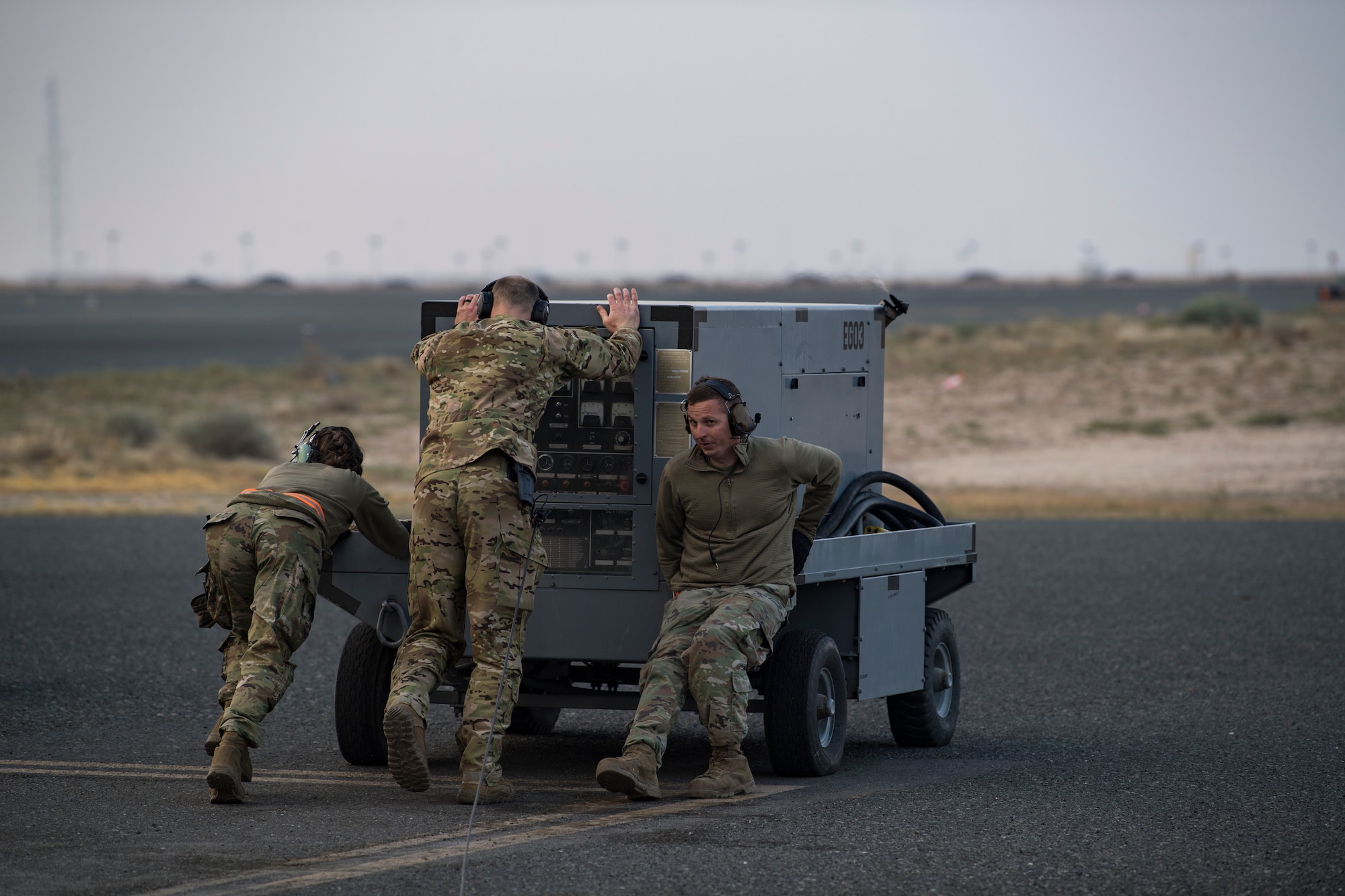 A U.S. Air Force loadmaster assigned to the 779th Expeditionary Airlift Squadron, helps crew chiefs push a power cart at Ali Al Salem Air Base, Kuwait, Feb. 20, 2020.