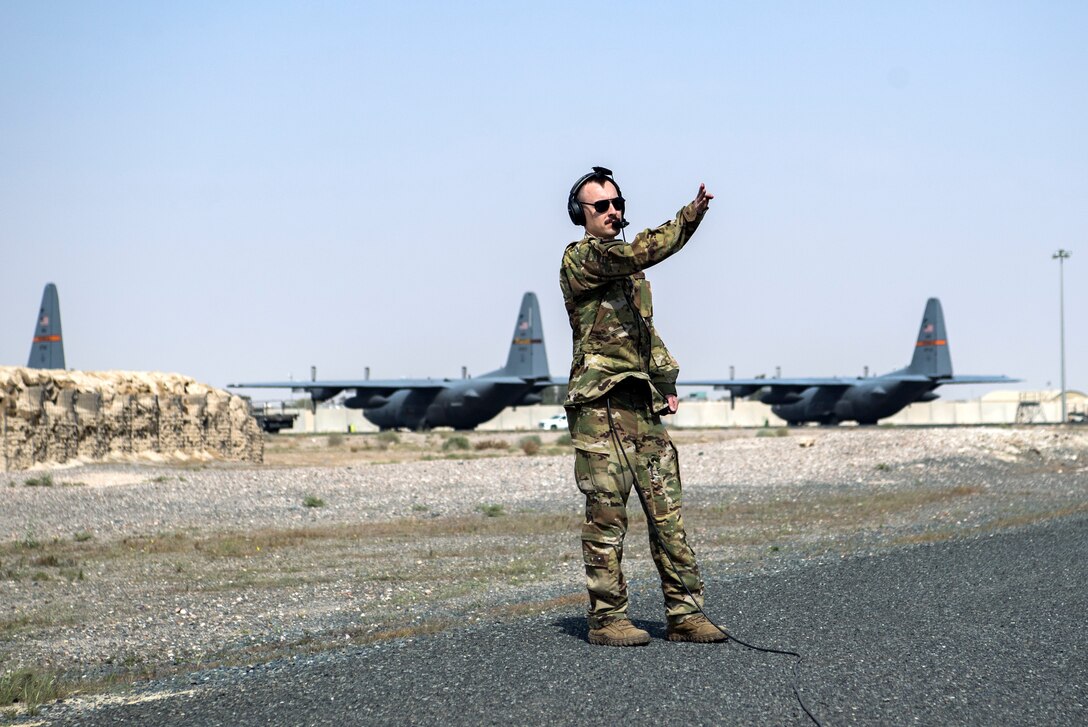 A U.S. Air Force loadmaster assigned to the 779th Expeditionary Airlift Squadron, signals to crew chiefs to remove a power cart from a C-130H Hercules during engine startup at Ali Al Salem Air Base, Kuwait, Feb. 20, 2020.
