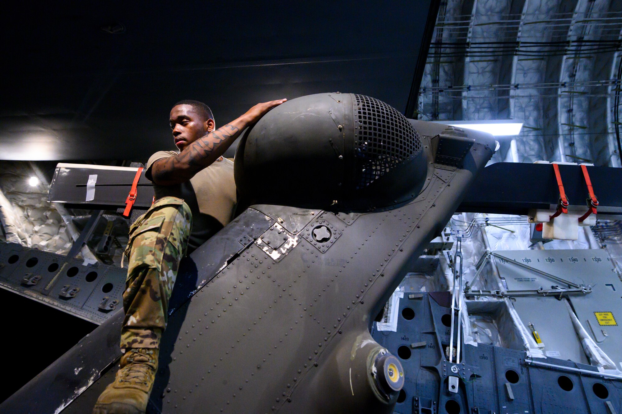 U.S. Army Spc. Devante Turner, 82nd Combat Aviation Brigade (CAB), 3rd Battalion crew chief, assists in unloading a UH-60 Black Hawk helicopter off a U.S. Air Force 21st Airlift Squadron C-17 Globemaster III aircraft
