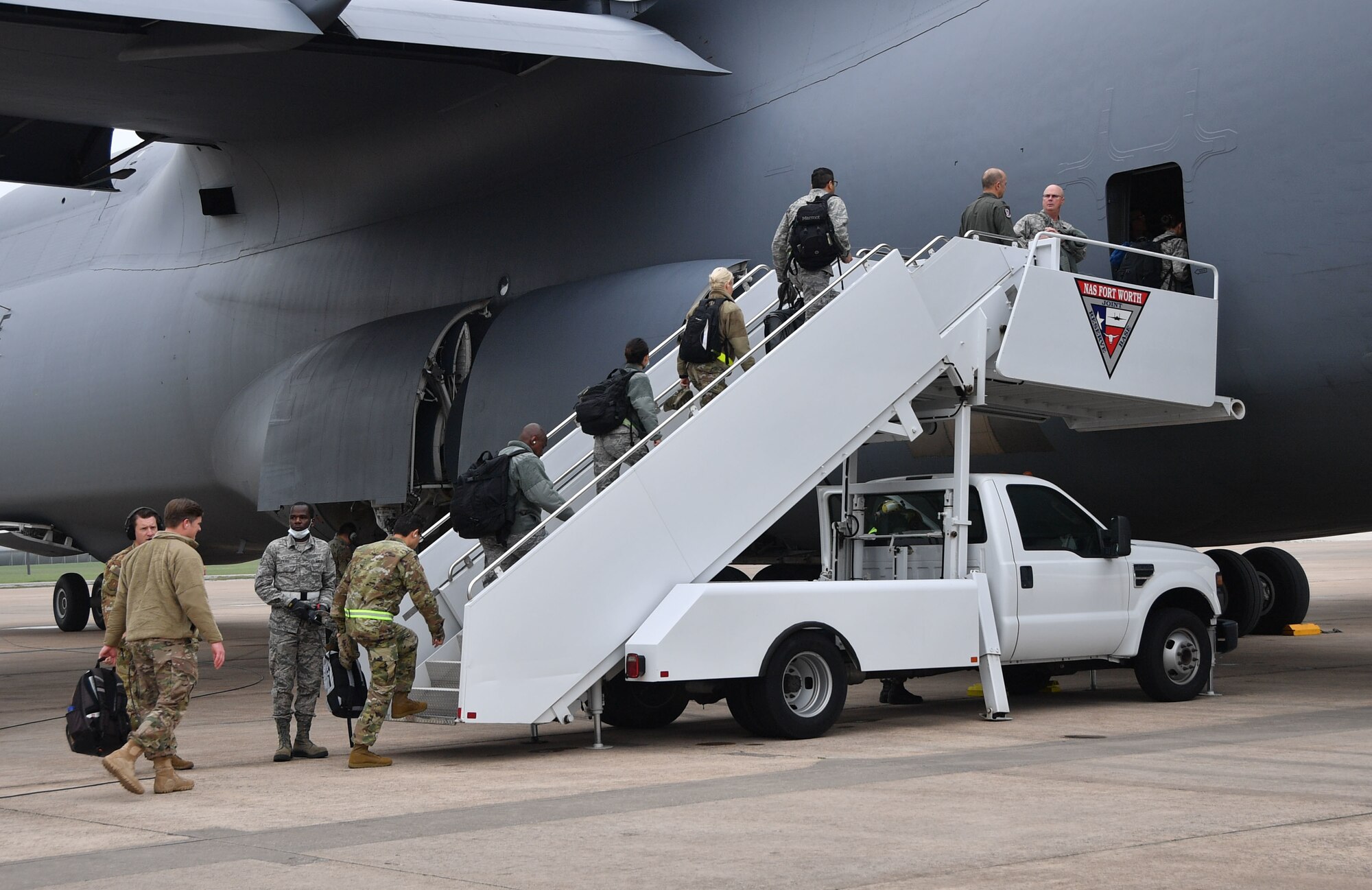 Deploying Airmen from the 301st Fighter Wing Medical Squadron board a C-5M Super Galaxy at U.S. Naval Air Station Joint Reserve Base, Fort Worth, Texas on April 5, 2020. This deployment is part of a larger mobilization package of more than 120 doctors, nurses, and respiratory technicians Air Force Reserve units across the nation provided over the past 48 hours of COVID-19 response to take care of Americans. (U.S. Air Force photo by Capt. Jessica Gross)
