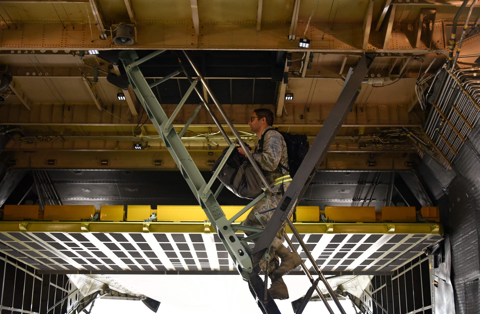 A deploying Airman from the 301st Fighter Wing Medical Squadron climbs stairs to the second level inside of a C-5 Super Galaxy at U.S. Naval Air Station Joint Reserve Base, Fort Worth, Texas on April 5, 2020. This deployment is part of a larger mobilization package of more than 120 doctors, nurses, and respiratory technicians Air Force Reserve units across the nation provided over the past 48 hours of COVID-19 response to take care of Americans. (U.S. Air Force photo by Tech. Sgt. Melissa Harvey)