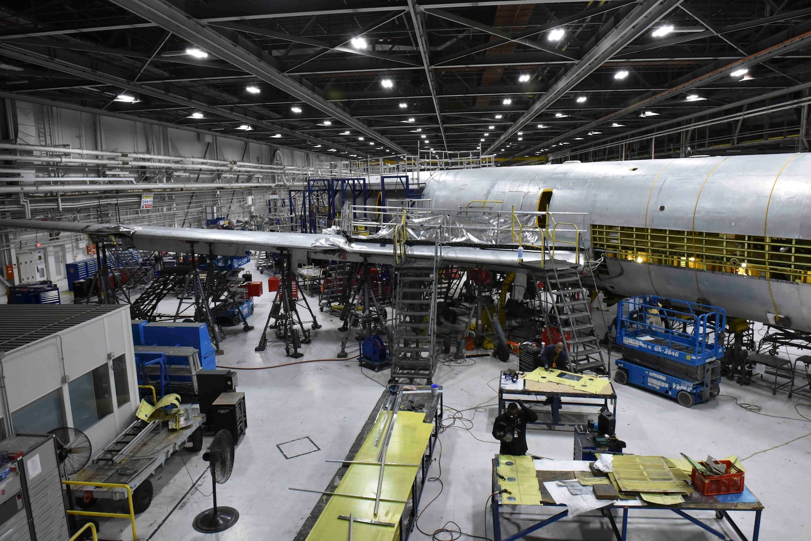 An aircraft sits broken down in a industrial facility.