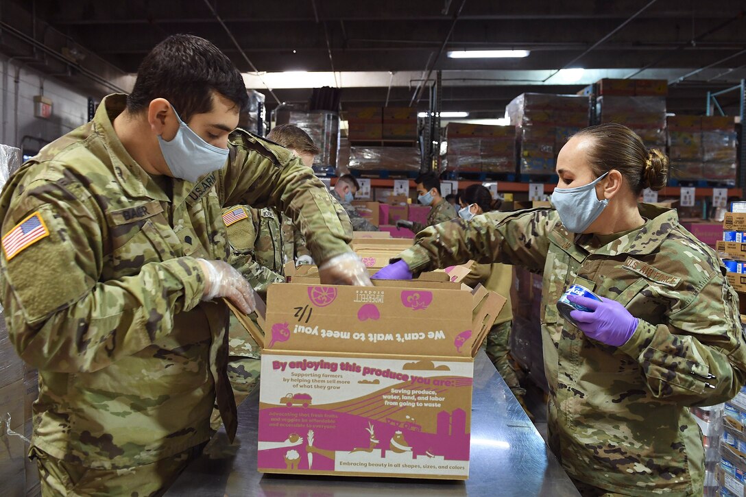 Soldiers and airmen pack food boxes.