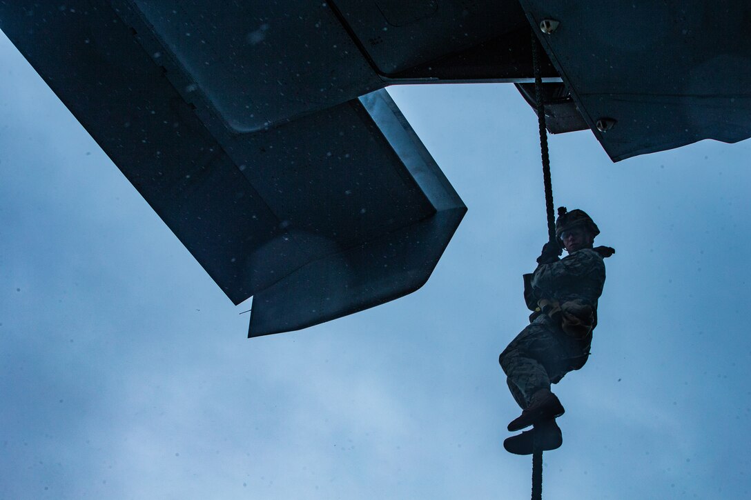 A Marine slides down a rope.