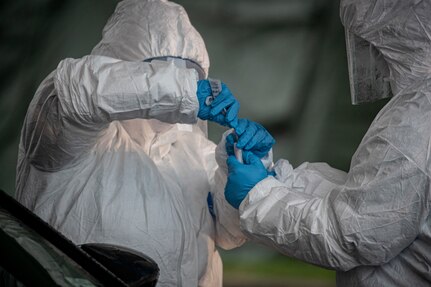 Medical staff process a patient sample at a COVID-19 testing site at the PNC Bank Arts Center in Holmdel, N.J., March 23, 2020. Airmen from the New Jersey Air National Guard’s 108th Wing and 177th Fighter Wing are providing security and traffic control at the site. This photo has been edited to remove personal information.