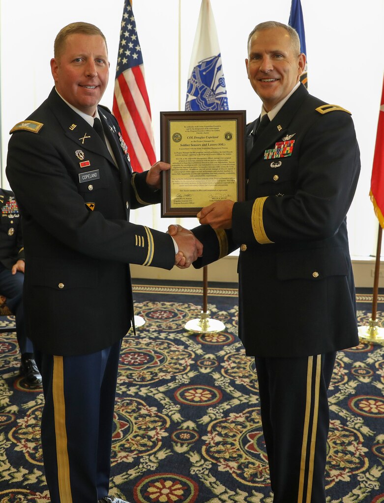 Brig. Gen. Anthony Potts, Program Executive Officer (PEO) Soldier, presents Col. Douglas W. Copeland, Project Manager Soldier Sensors and Lasers (PM SSL) at Program Executive Office Soldier, the PM SSL Charter, at Fort Belvoir, Va., July 26, 2019.  Copeland relieved Col. Christopher D. Schneider during the PM SSL change of charter.