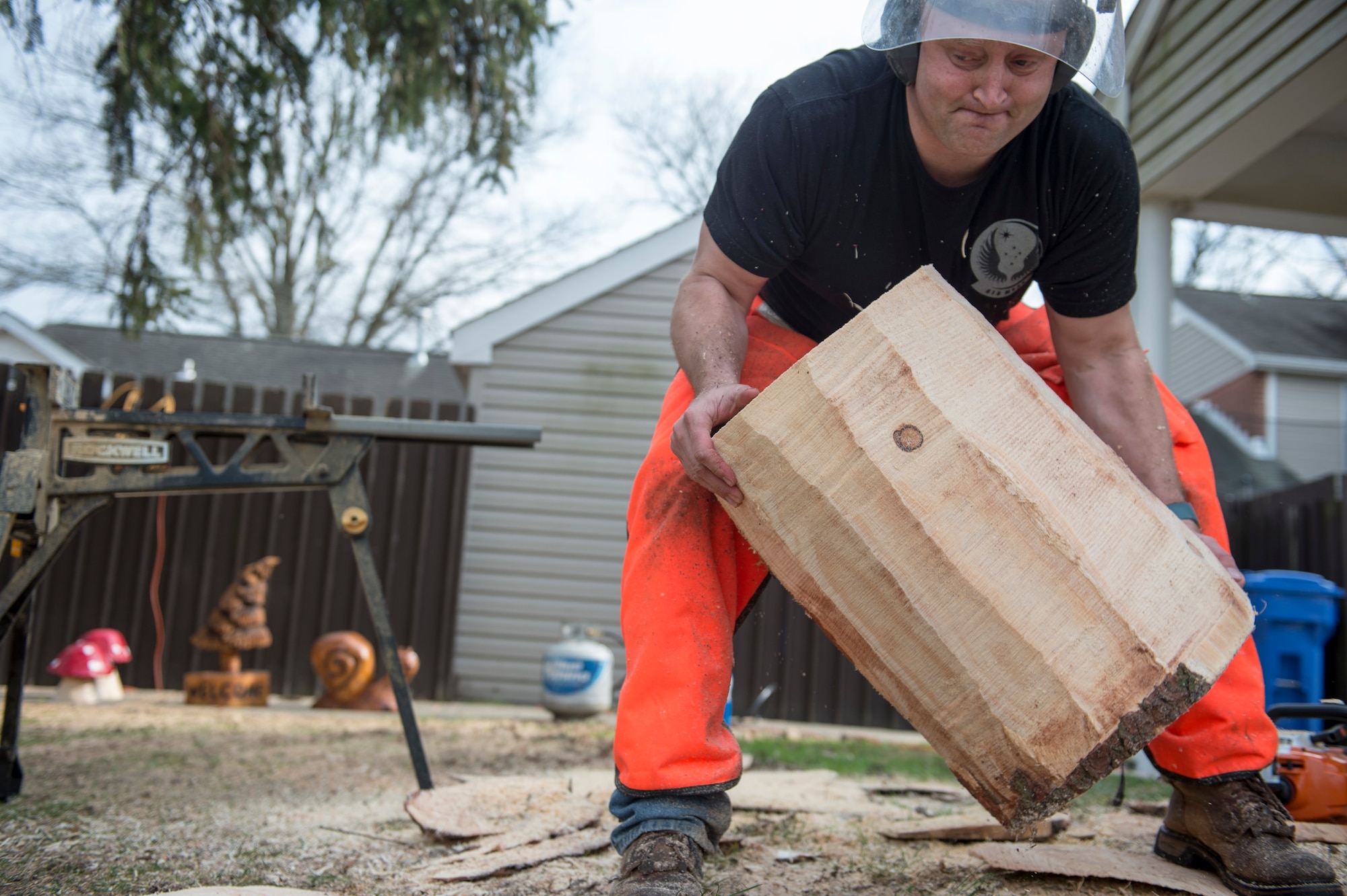 U.S. Air Force Tech. Sgt. Scott Herbert, 818th Mobility Support Advisory Squadron air advisor, moves a log to his work station to start carving an art piece March 12, 2020, at his house on Joint Base McGuire-Dix-Lakehurst, New Jersey. Herbert has been practicing chainsaw art for two years and has carved owls, eagles, rams, snails, trees, pumpkins, fish and bears. (U.S. Air Force photo by Staff Sgt. Sarah Brice)