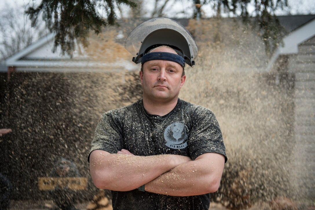 U.S. Air Force Tech. Sgt. Scott Herbert, 818th Mobility Support Advisory Squadron air advisor, is surrounded by the sawdust he produced during the initial cutting stage of his wooden bear statue March 12, 2020, Joint Base McGuire-Dix-Lakehurst, New Jersey. Herbert has been practicing chainsaw art for two years and has carved owls, eagles, rams, snails, trees, pumpkins, fish and bears. (U.S. Air Force photo by Staff Sgt. Sarah Brice)