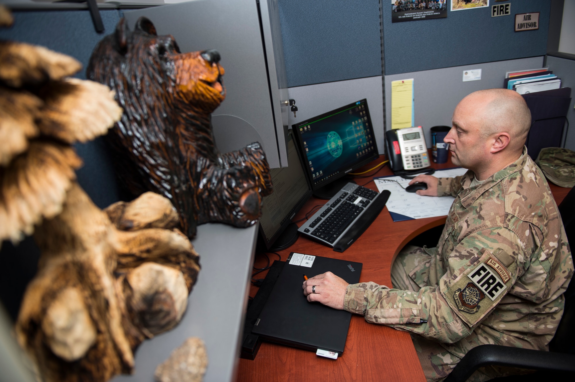 U.S. Air Force Tech. Sgt. Scott Herbert, 818th Mobility Support Advisory Squadron air advisor, answers emails at his office which is decorated with some of his chainsaw carvings April 1, 2020, Joint Base McGuire-Dix-Lakehurst, New Jersey. Herbert says that carving is his way to find peace and calm during his busy family, work, and church life. (U.S. Air Force photo by Staff Sgt. Sarah Brice)
