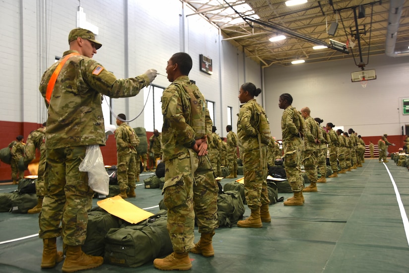 A group of soldiers waits to have their temperatures taken.