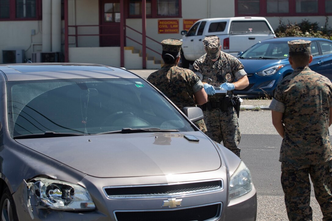 U.S. Marine Lance Cpl. Paul McGary, a military police officer with the Provost Marshal’s Office, Security and Emergency Services Battalion, Marine Corps Base Camp Pendleton, takes down service members’ information during a traffic collision on Camp Pendleton, California, April 3, 2020. The security services and first responders on Camp Pendleton are taking precautions to prevent the spread of COVID-19. Military police are asking base patrons if they have any flu like symptoms before assisting them in any situation. (U.S. Marine Corps photo by Lance Cpl. Andrew Cortez)