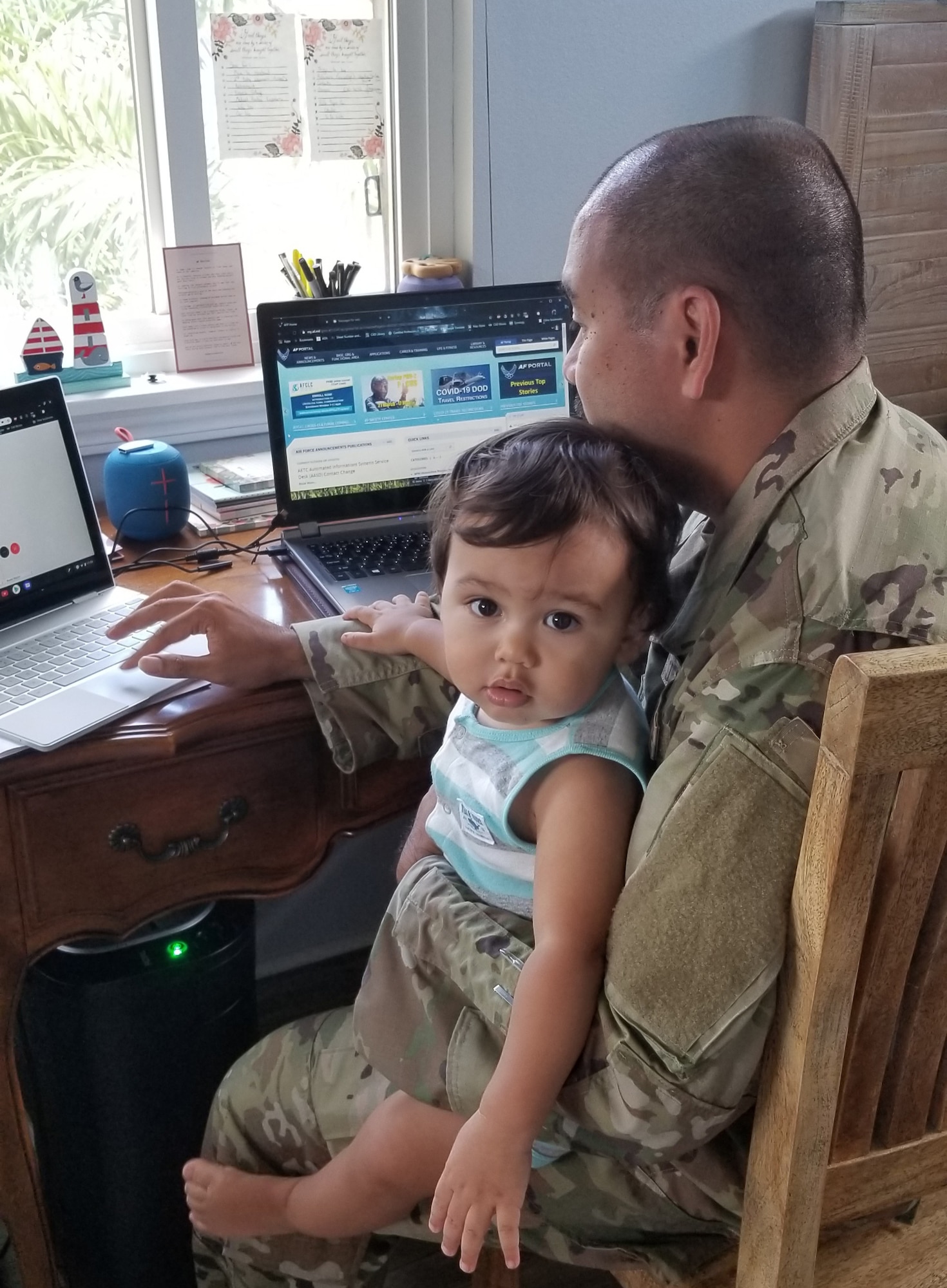 A photo of U.S. Air Force Staff Sgt. Charlie Trilles, a 624th Civil Engineer Squadron Engineering Journeyman, teleworking with his son Evan during the 624th Regional Support Group virtual unit training assembly April 4, 2020, from his home in Honolulu, Hawaii. Like many of the people in the U.S., Reserve Citizen Airmen in Hawaii and Guam are adapting to family and work requirements during the first-ever 624th RSG virtual UTA, which was implemented to help keep Airmen safe during COVID-19 pandemic. (Courtesy Photo)