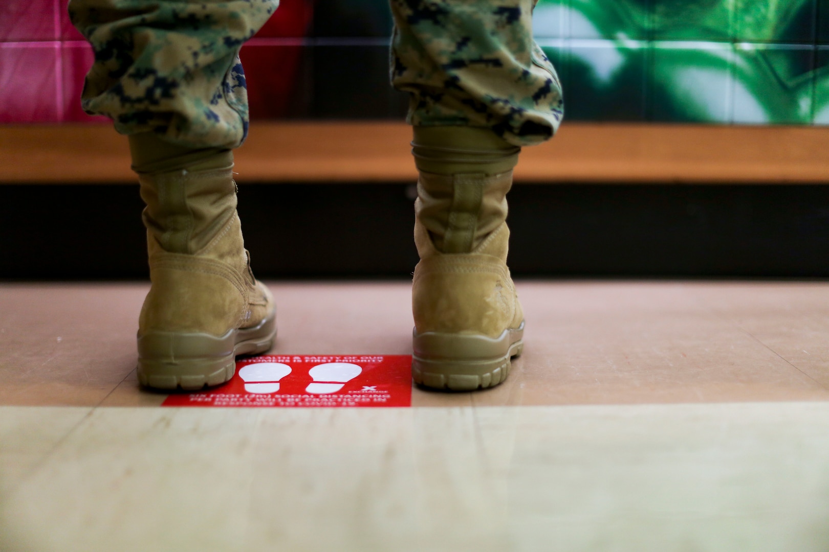 A service member stands by a red sign with footprints on the floor.