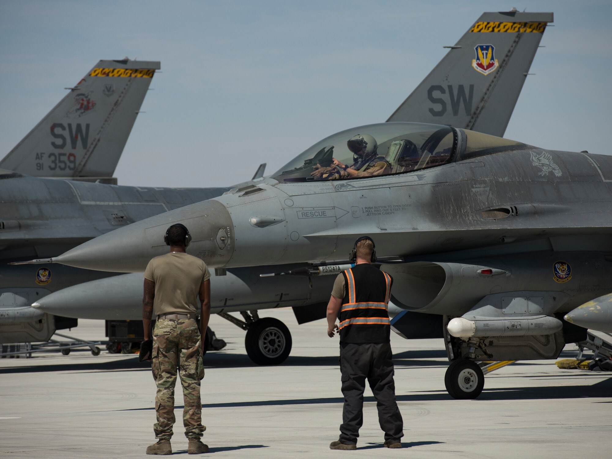 U.S Air Force Staff Sgts. Nathan Stokes, left, and U.S Air Force Staff Sgt. David Williams, crew chiefs with the 380th Expeditionary Aircraft Maintenance Squadron, wait to marshal a U.S. Air Force F-16 “Viper” Fighting Falcon assigned to the 79th Expeditionary Fighter Squadron at an undisclosed location in the U.S. Central Command area of responsibility, Feb. 24, 2020.