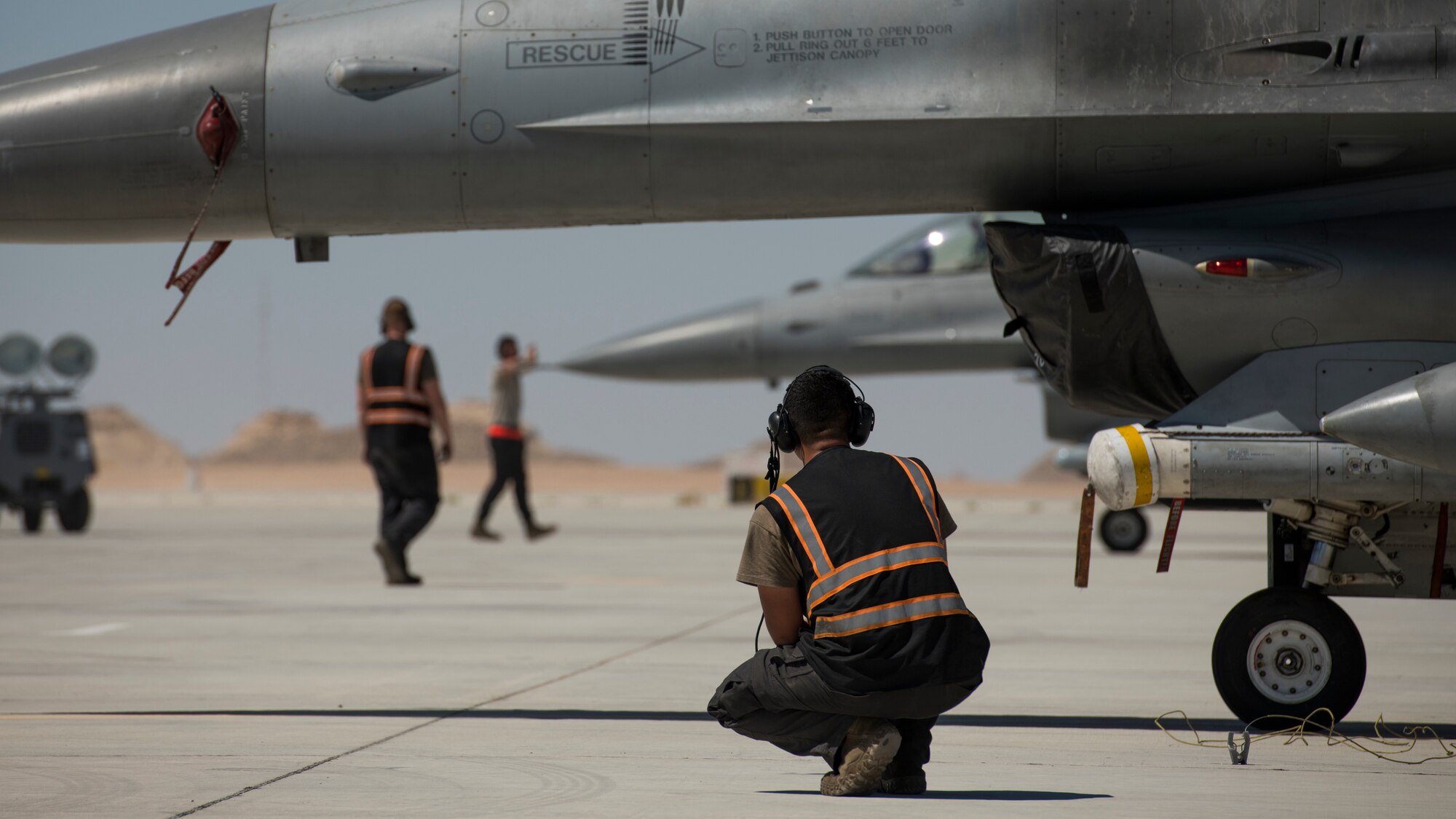 U.S Air Force Airman 1st Class Michael Tobat, a crew chief with the 380th Expeditionary Aircraft Maintenance Squadron, looks on as Airmen marshal U.S. Air Force F-16 “Viper” Fighting Falcons assigned to the 79th Expeditionary Fighter Squadron at an undisclosed location in the U.S. Central Command area of responsibility, Feb. 24, 2020.