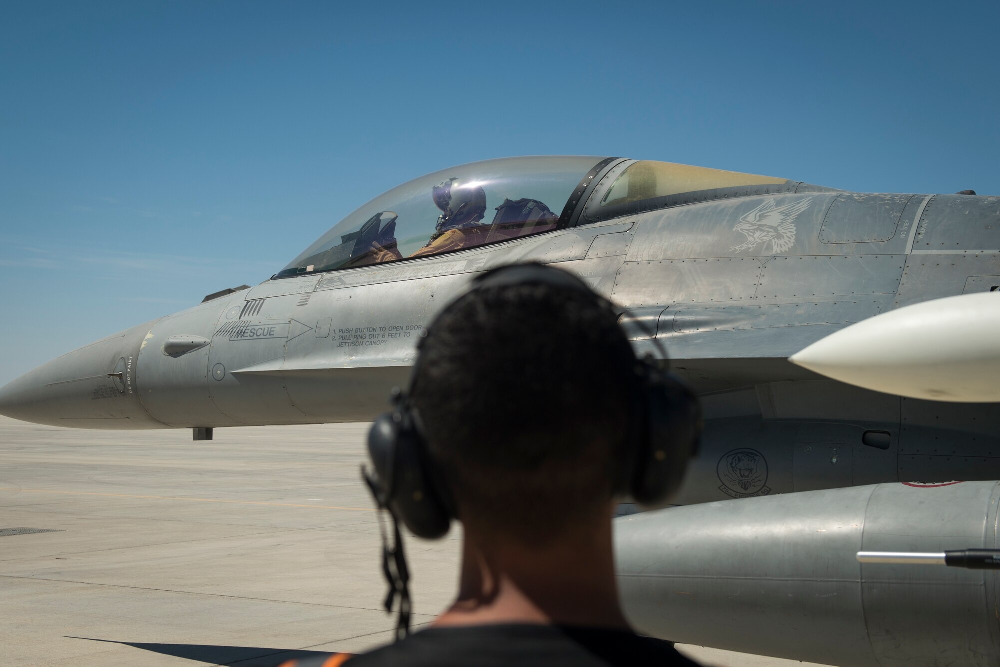 U.S Air Force Airman 1st Class Michael Tobat, a crew chief with the 380th Expeditionary Aircraft Maintenance Squadron, looks on as a U.S. Air Force F-16 “Viper” Fighting Falcon pilot assigned to the 79th Expeditionary Fighter Squadron prepares to takeoff at an undisclosed location in the U.S. Central Command area of responsibility, Feb. 24, 2020.