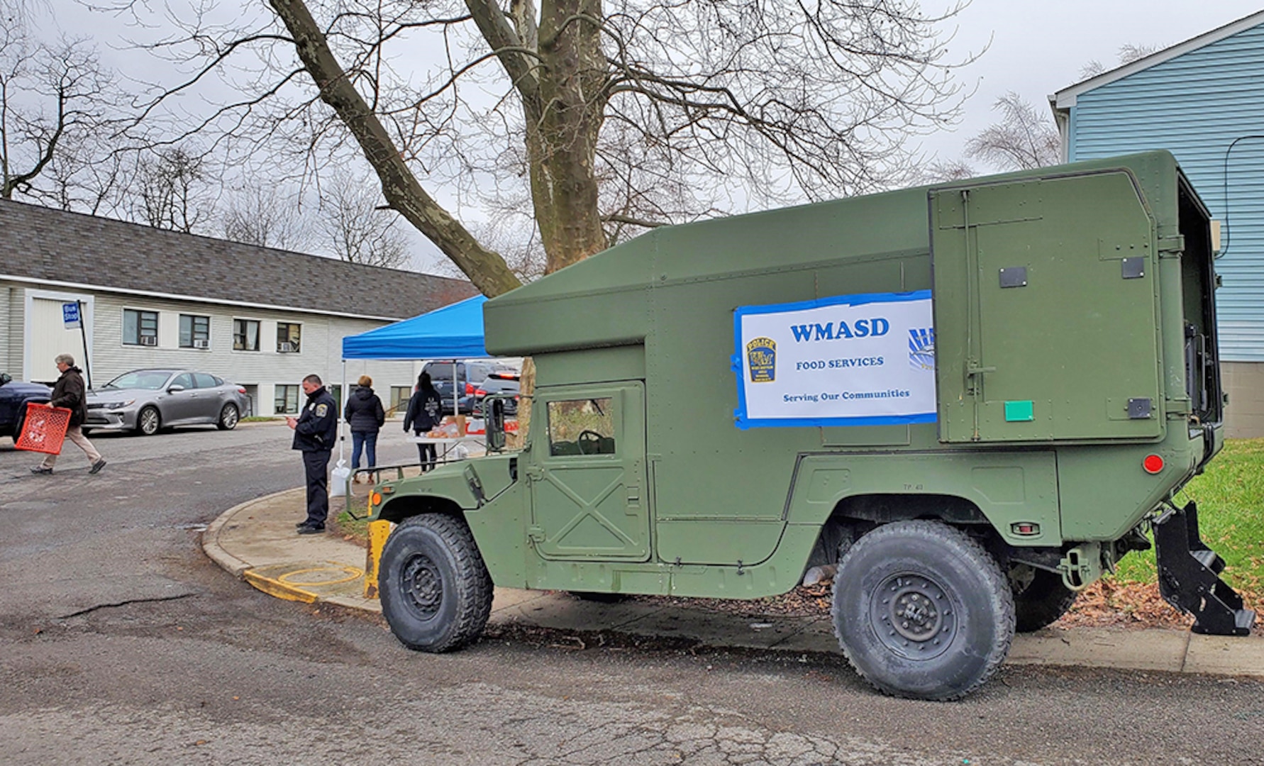 A former military ambulance is parked on a street corner food donation location.