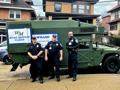 Police officers pose in front of a surplus military truck they received.