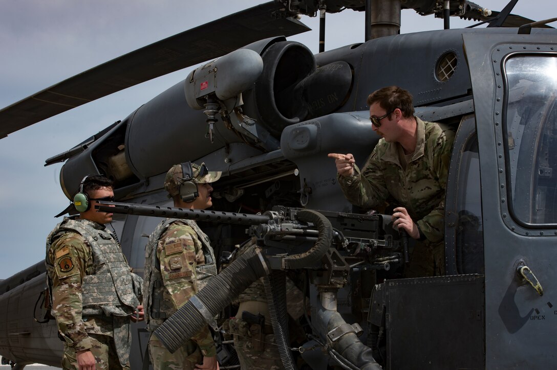 A U.S. Air Force special mission aviator assigned to the 66th Expeditionary Rescue Squadron explains the weapons capabilities of a HH-60G Pave Hawk during a training exercise near Al Udeid Air Base, Qatar, March 24, 2020.