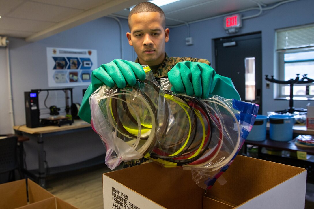 U.S. Marine Corps Cpl. Michael Espinosa with Makerspace, 2nd Marine Logistics Group packs 3-D printed face masks into a box on Camp Lejeune, N.C., March, 2020. Marines from Makerspace utilized 3-D printing to rapidly manufacture personal protective equipment to be sent to aid FEMA Region 8 and 2nd Medical Battalion in COVID-19 screening. (U.S. Marine Corps photo by Lance Cpl. Scott Jenkins)