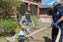 Latavis Johnson, right,  and Senior Airman Jacob Tripaldi, left, firefighters assigned to the 628th Civil Engineering Squadron Fire Department, attach a hose to a fire hydrant in Hunley Park-Air Base housing on Joint Base Charleston, S.C., March 25, 2020. The Fire Department is still conducting normal operations. Firefighters are taking preventative measures such as cleaning common areas every four hours, and enforcing higher hygiene standards like frequently washing hands.