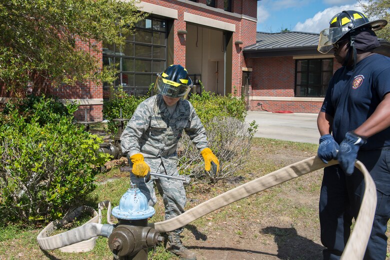 Latavis Johnson, right,  and Senior Airman Jacob Tripaldi, left, firefighters assigned to the 628th Civil Engineering Squadron Fire Department, attach a hose to a fire hydrant in Hunley Park-Air Base housing on Joint Base Charleston, S.C., March 25, 2020. The Fire Department is still conducting normal operations. Firefighters are taking preventative measures such as cleaning common areas every four hours, and enforcing higher hygiene standards like frequently washing hands.