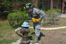 Senior Airman Jacob Tripaldi, a firefighter assigned to the 628th Civil Engineering Squadron Fire Department, works to open a fire hydrant after attaching a hose in Hunley Park-Air Base housing on Joint Base Charleston, S.C., March 25, 2020. The Fire Department is still conducting normal operations. Firefighters are taking preventative measures such as cleaning common areas every four hours, and enforcing higher hygiene standards like frequently washing hands.