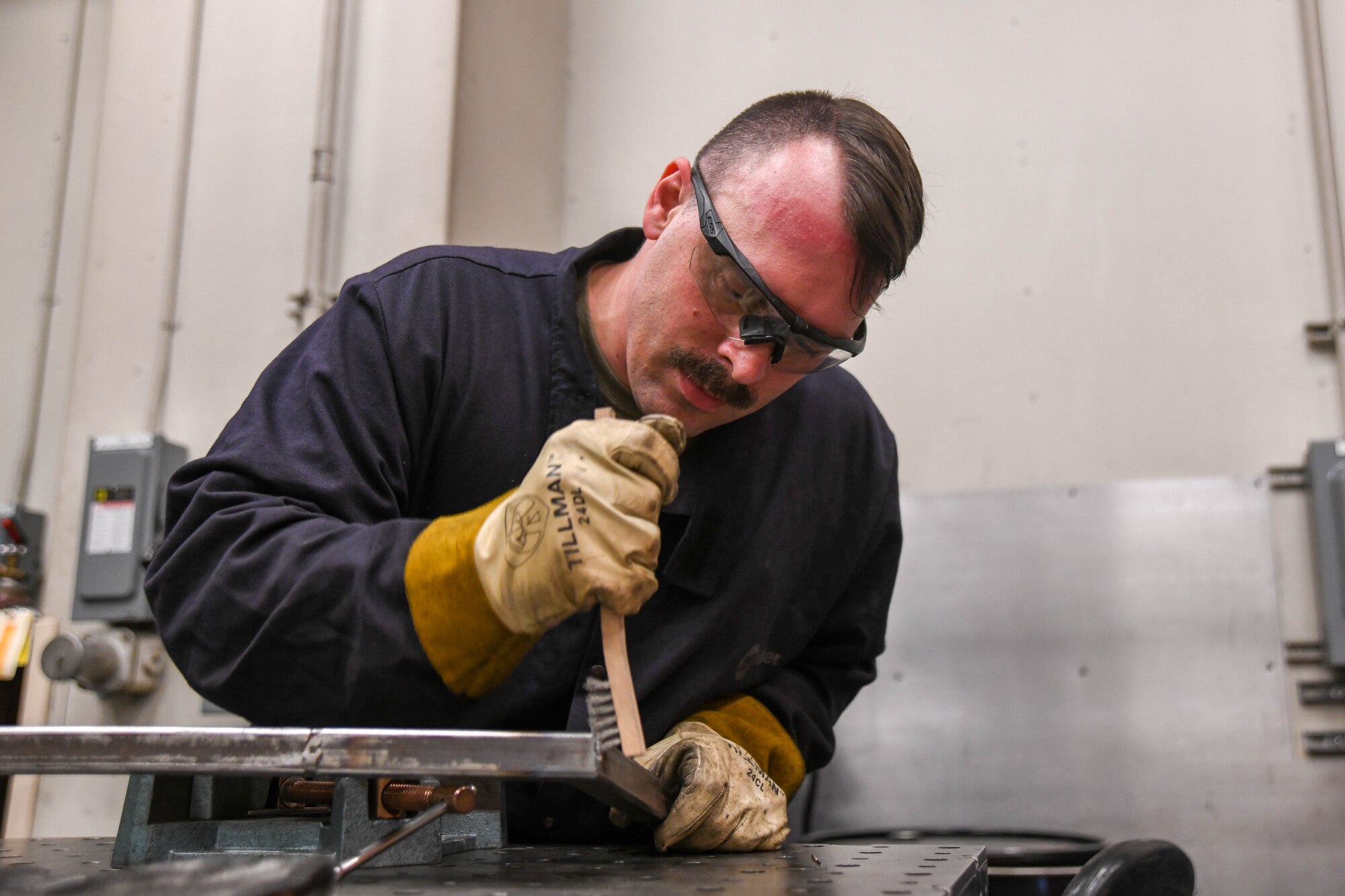 Staff Sgt. Derrick Wilkins, 22nd Maintenance Squadron aircraft metals technology craftsman, brushes over the welded seams he created March 24, 2020, at McConnell Air Force Base, Kansas. The wire brush is used during post-weld cleaning to ensure there are no contaminants that may have adhered to the metal during the welding process. A technician’s precision and attention to detail is essential in supporting mission productivity. (U.S. Air Force photo by Airman 1st Class Nilsa E. Garcia)