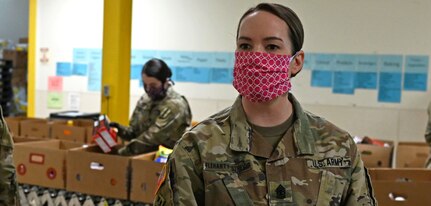 1st Sgt. Rachael Fleharty-Strevig, Headquarters and Service Company, 3643d Brigade Support Battalion, New Hampshire National Guard, sorts through dry goods at the N.H. Food Bank in Manchester.