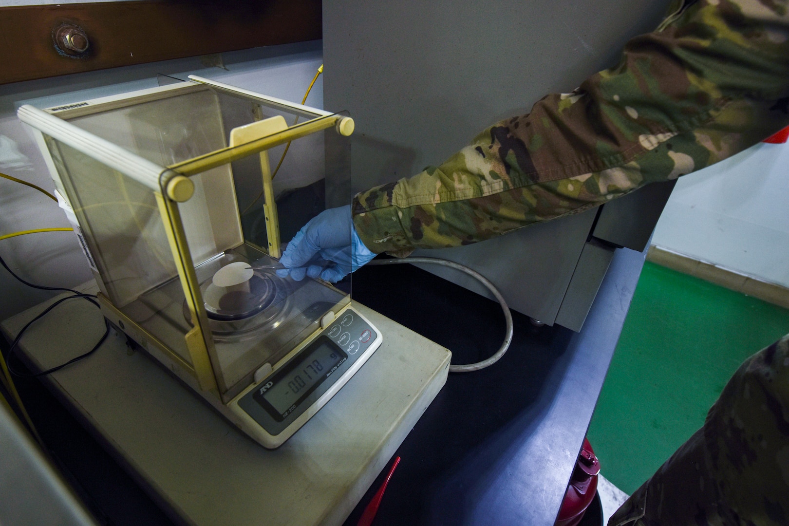 U.S. Air Force Senior Airman Cody Lane, 8th Logistics Readiness Squadron fuels laboratory technician, weighs a pad on a scale in the fuels laboratory at Kunsan Air Base, Republic of Korea, April 3, 2020. These pads are weighed before a gallon of fuel is run through it and then weighed again after in order for the technician to know how much sediment is in the fuel. (U.S. Air Force photo by Senior Airman Jessica Blair)