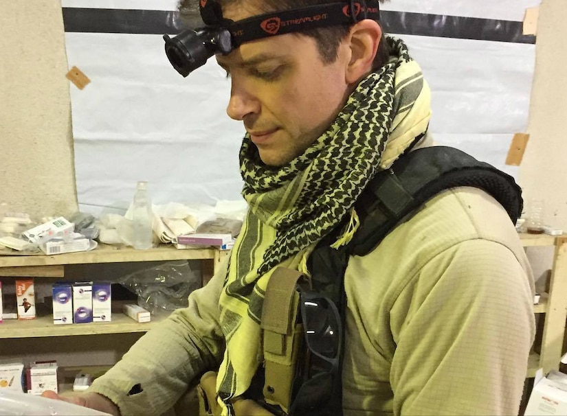 Environmental portrait of a doctor who has a light strapped to his forehead as he works.