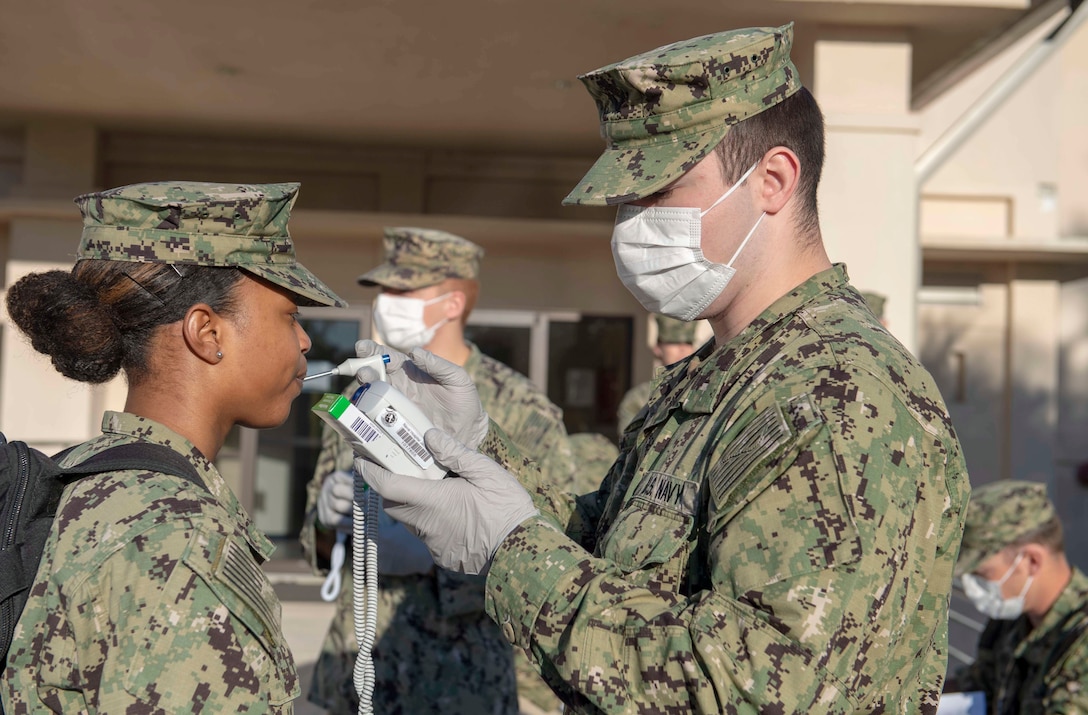 A sailor gets her temperature taken.