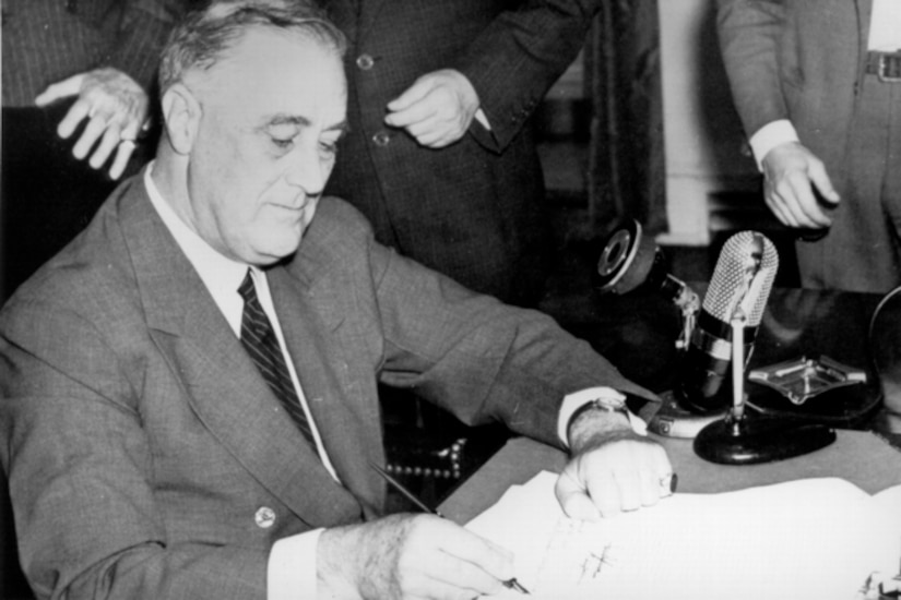 Seated man signs document.