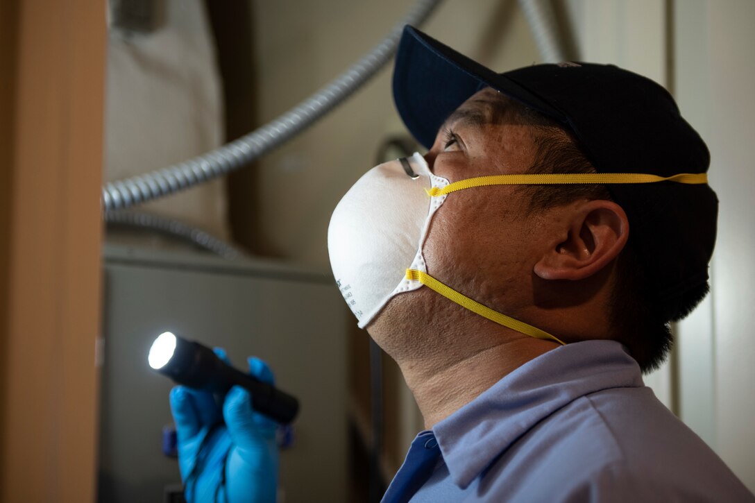 A photo of a worker inspecting an air conditioner.