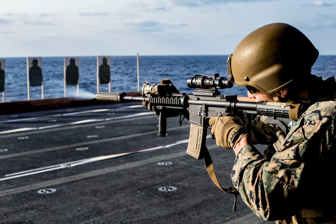A Marine fires a weapon on a ship.