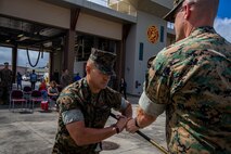 U.S. Marine Corps Sgt. Maj. Jose Romero, on-coming sergeant major, Marine Corps Air Station Kaneohe Bay, receives the sword of office from Lt. Col. Tyler Holland, commanding officer, MCAS, during the MCAS relief and appointment ceremony, Marine Corps Base Hawaii, March 27, 2020. Sgt. Maj. Juarice Collins relinquished responsibilities to Sgt. Maj. Jose Romero. Collins retired after 23 years of honorable and faithful service. (U.S. Marine Corps photo by Cpl. Matthew Kirk)
